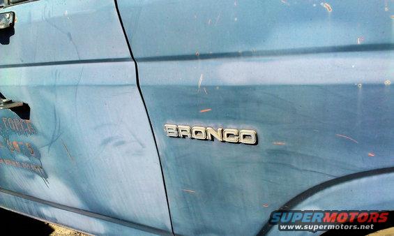 Blue Ford Bronco side panel with 'BRONCO' badge. Some text is visible on the door