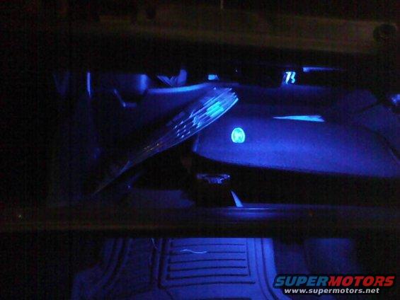 Dashboard of a 2003 Ford Crown Victoria with blue interior lighting, showing the steering wheel and part of the instrument cluster