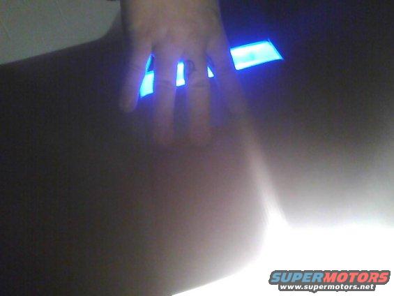 Hand with a ring on a finger over blue illuminated interior lights