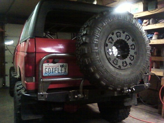 Red SUV's rear bumper with a large spare tire mounted. Washington license plate reads 'GOTFLEX'