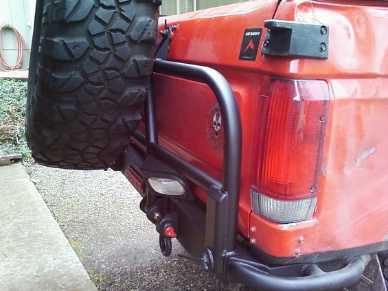 Red SUV rear with spare tire carrier and custom bumper. 1989 Ford Bronco