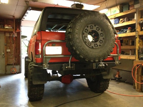 Red SUV rear view with spare tire carrier and mud flaps