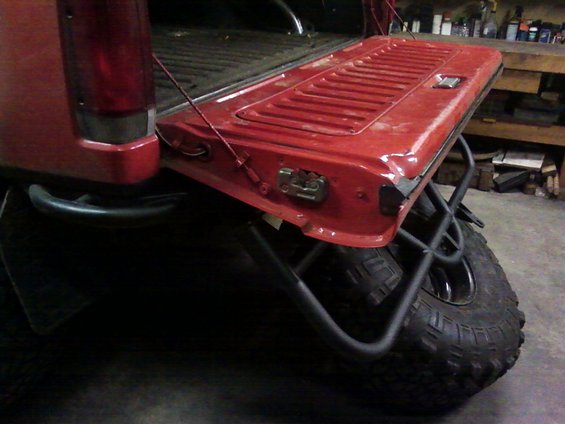 Red tailgate with a custom tube spare tire carrier mounted below it