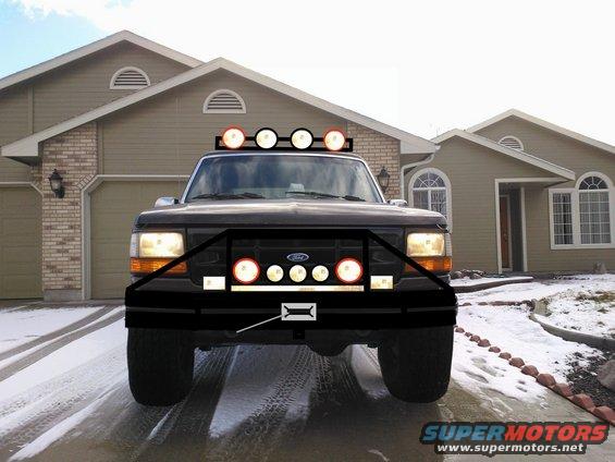 Front view of a dark Ford F-Series truck with a brush guard and lights on the roof and bumper. It's parked in a driveway with snow on the ground