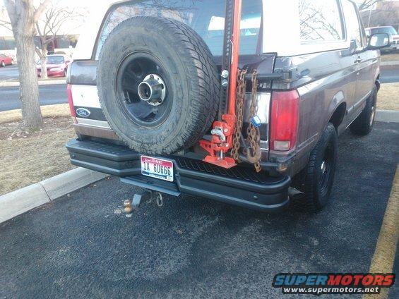 Brown 1992 Ford Bronco rear with spare tire, jack, and chains mounted. License plate visible