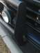 1992 Ford Bronco - A black brush guard is mounted on the front of a vehicle, obscuring part of the grille and two auxiliary lights.