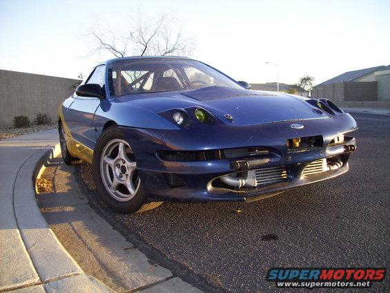 Blue 1993 Ford Probe with front-mounted intercooler and racing roll cage, parked on a street