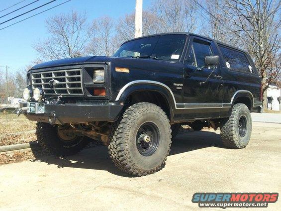 Black 1980 Ford Bronco with off-road tires and aftermarket bumper, viewed from the front three-quarter angle