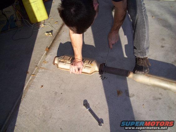 Catalytic converter being worked on by a person on a concrete surface