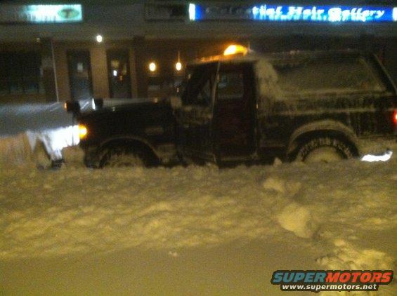 1989 Ford Bronco stuck in deep snow, front end partially obscured