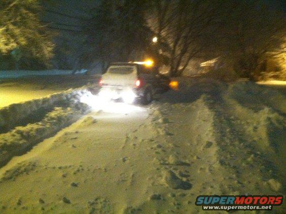 White SUV with orange light on roof driving in snow at night