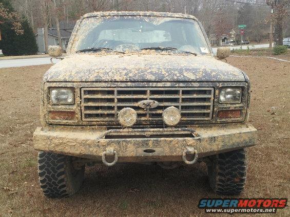 Mud-covered 1986 Ford Bronco front view with aftermarket bumper and lights