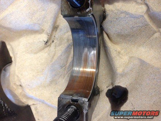 worn engine bearing with rust and oil stains on shop towel
