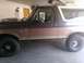 1992 Ford Bronco - Side view of a brown and white 1992 Ford Bronco with yellow trim, parked indoors.