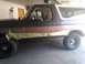 1992 Ford Bronco - A 1992 Ford Bronco is shown in a garage with masking tape applied to the lower body panels, likely in preparation for painting.