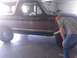 1992 Ford Bronco - A person inspects the side of a brown 1992 Ford Bronco with a white top.