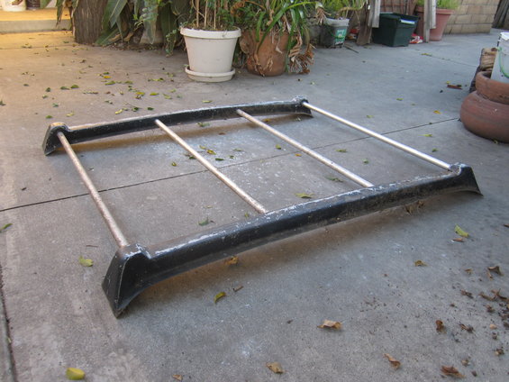 Black roof rack part with silver bars on concrete