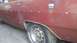 1988 Ford Bronco - Close-up of a red car's side panel, showing the wheel well and a fuel filler cap.