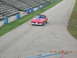 2003 Ford Crown Victoria - A red convertible sports car is seen on a race track with bleachers in the background.