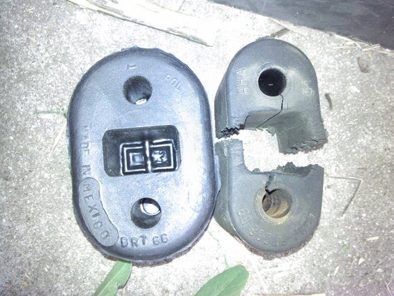 Two broken rubber exhaust hangers, one labeled 'MADE IN MEXICO DRT 66', the other cracked and split