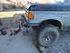 1990 Ford Bronco - The front quarter panel of a 1990 Ford Bronco shows a custom bumper and welding gear on the ground.