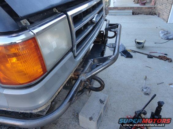 Gray Ford truck front end with custom brush guard, orange turn signal, chrome grille, and tow hooks