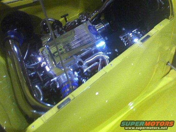 Yellow car engine bay with chrome components and blue accents