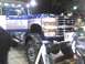 2003 Ford Crown Victoria - A blue and silver Ford F-Series truck is displayed indoors, a prominent chrome grille and large tires.
