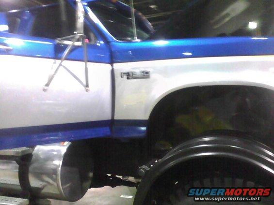 Blue and white Ford F-350 truck side view, showing door, fender, and large wheel