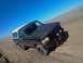 1992 Ford Bronco - A brown and white 1992 Ford Bronco drives off-road under a clear blue sky.