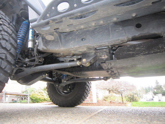 Undercarriage of a modified Jeep Wrangler with large tires and blue shocks, viewed from the front