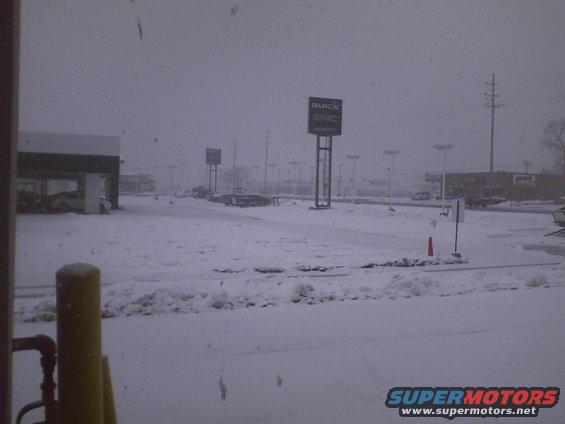 Snowy parking lot with Buick and GMC signs visible, multiple cars parked
