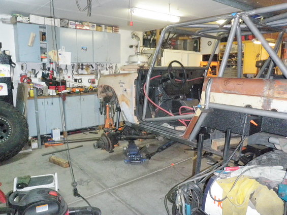 1961 International Scout in a garage, undergoing repairs with a roll cage installed