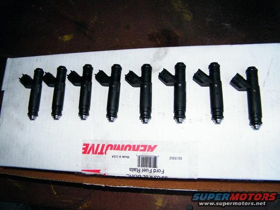 Eight black fuel injectors laid out on a white box labeled 'Ford Fuel Rails'