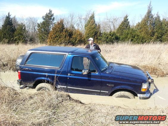 1995 Ford Bronco stuck in mud with a person standing by it