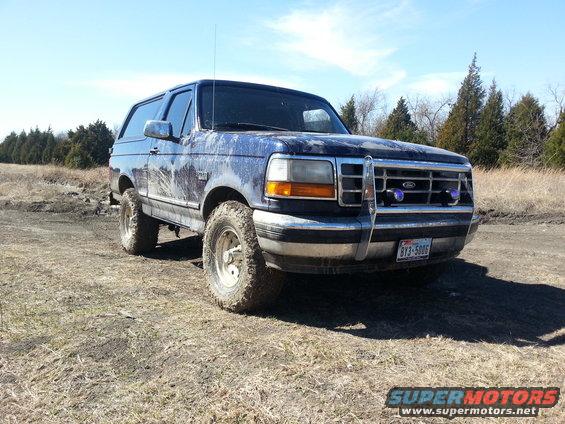 1995 Ford Bronco parked on a dirt road, covered in mud. License plate reads B73-5006