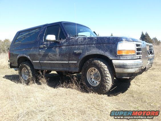 1995 Ford Bronco parked in dry grass with mud on its body