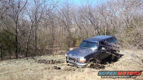 Dark blue 1995 Ford Bronco stuck in mud, 3/4 front view