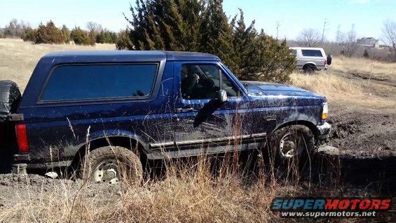 Blue 1995 Ford Bronco stuck in mud, another white Bronco in background