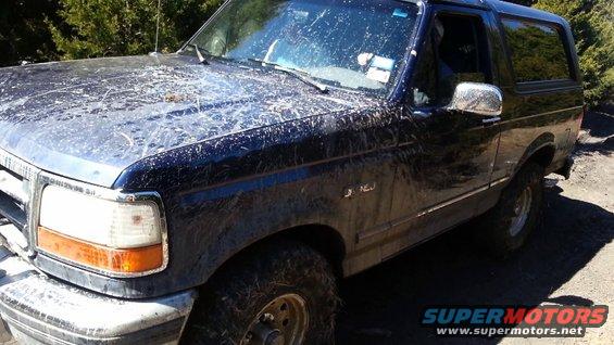 Dark blue Ford Bronco covered in mud, front quarter view