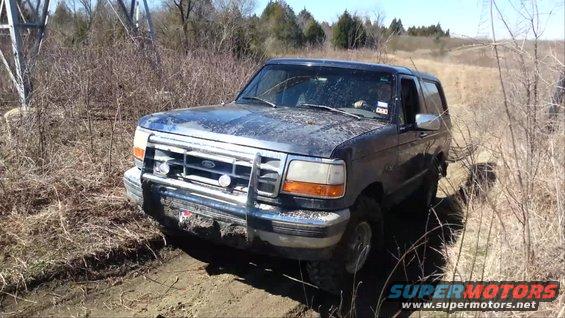 1995 Ford Bronco driving on a dirt trail through dry brush