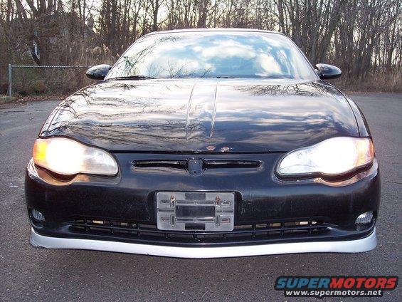 Front view of a black Chevrolet Monte Carlo with its headlights on