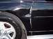 2002 Chevrolet Monte Carlo - Damage is visible on the fender and door seam of a black car, with rust appearing at the bottom.