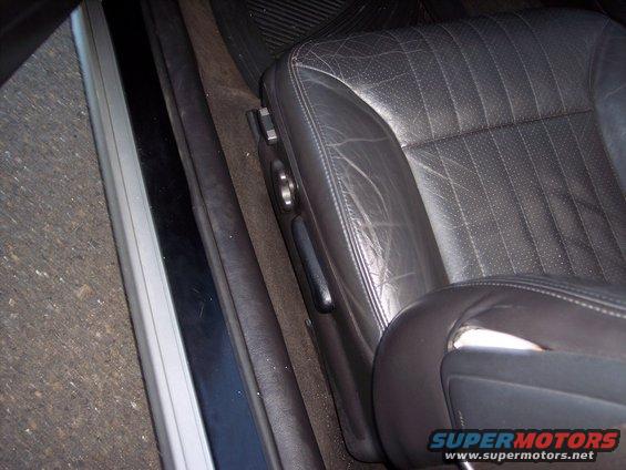 Close-up of worn black leather driver's seat with visible stitching and perforation detail