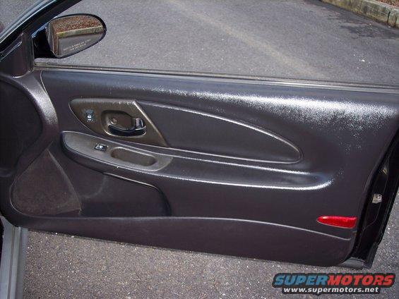 Interior of a car door, showing the armrest, door handle, and window controls