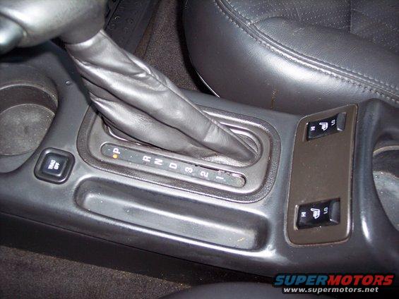 Car interior showing automatic gear shifter with P R N D 3 2 1 indicators and heated seat buttons