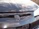 2002 Chevrolet Monte Carlo - Close-up of a black car's hood showing a damaged emblem and rust spots.