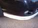 2002 Chevrolet Monte Carlo - Close-up of a damaged black car bumper with white lower trim, parked on asphalt.