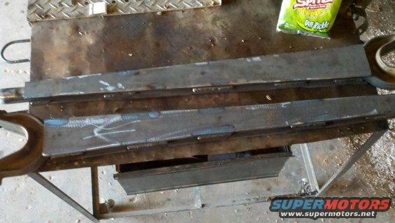 Welded metal parts on a workbench with a bag of dill pickle chips
