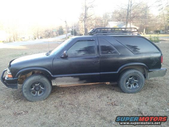 Black SUV with roof rack, side view. Appears to be a Chevrolet Blazer